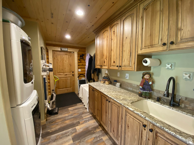 79 Auburn Forest Road Auburn, WY 83111 - Photo 26 of 76 Kitchen with dark wood finished floors, recessed lighting, light stone counters, stacked washer / drying machine, and rustic walls
