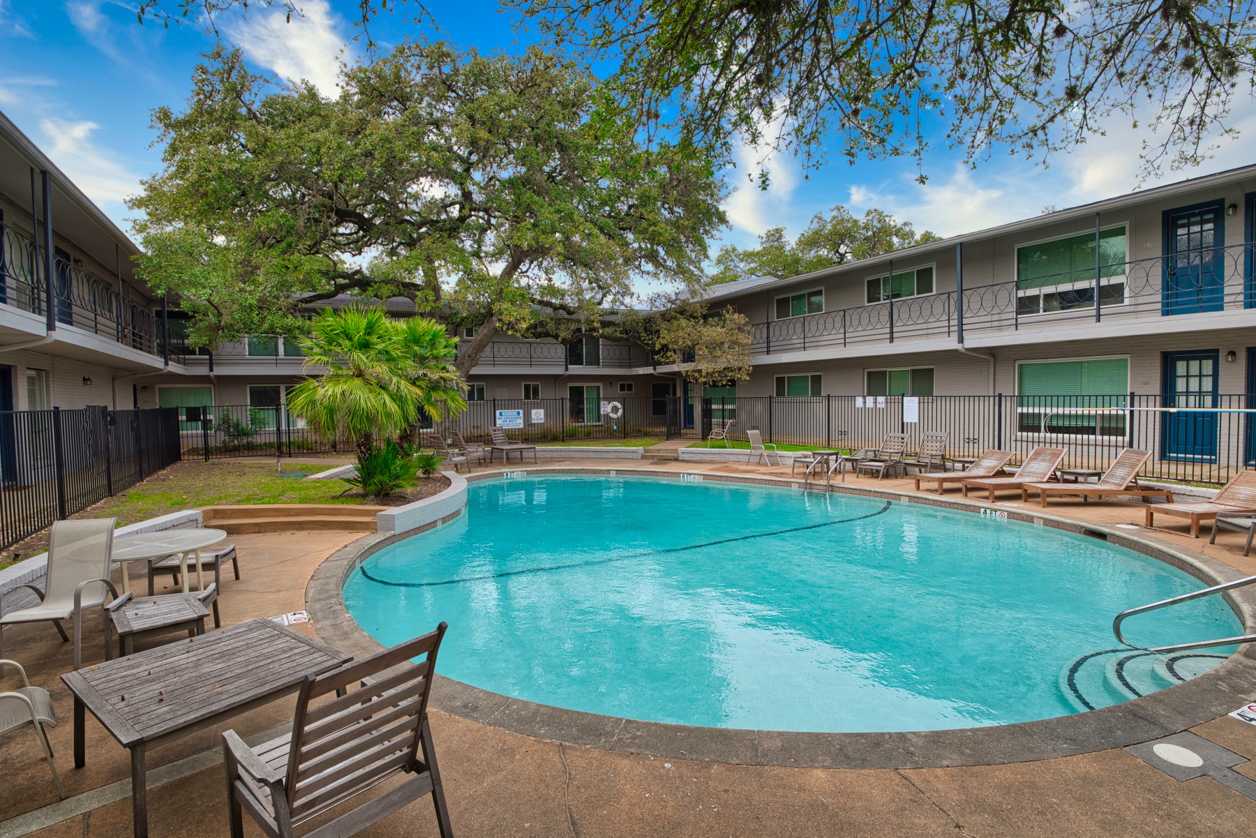 1210 Windsor Road, Unit 119 Austin, TX 78703 - Photo 13 of 15 Mature trees frame a sparkling swimming pool in a welcoming courtyard setting.