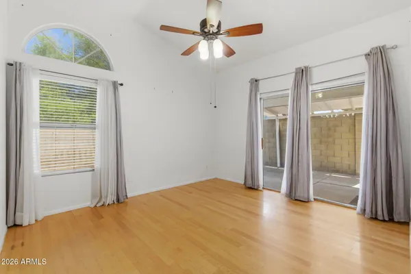 a view of an empty room with chandelier fan and wooden floor
