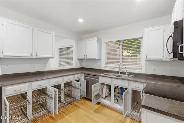 a kitchen with granite countertop white cabinets sink and window