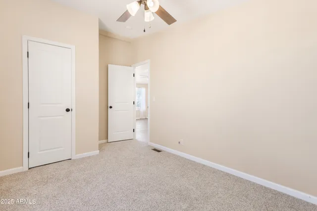 an empty room with chandelier fan and windows