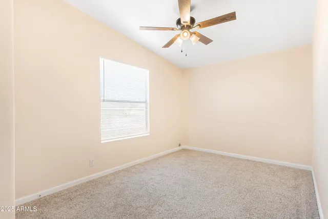 an empty room with a ceiling fan and a window