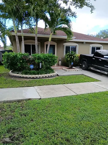 a front view of a house with a yard and potted plants