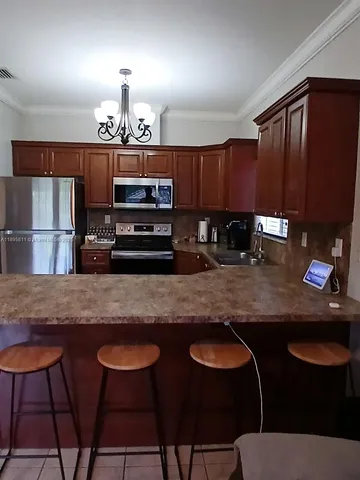 a kitchen with stainless steel appliances granite countertop a sink a stove a dining table and chairs