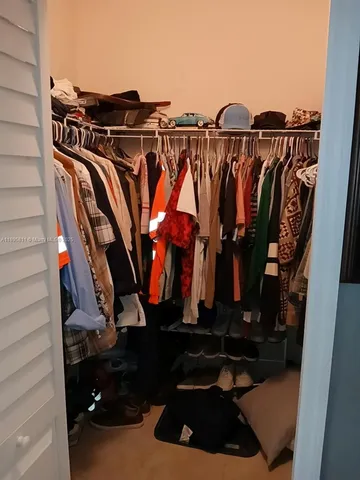 a view of walk in closet with clothes and shoes