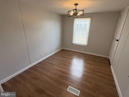 an empty room with wooden floor exposed radiator and windows
