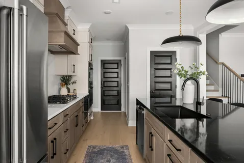 a kitchen with stainless steel appliances granite countertop a refrigerator a sink dishwasher a dining table and chairs with wooden floor