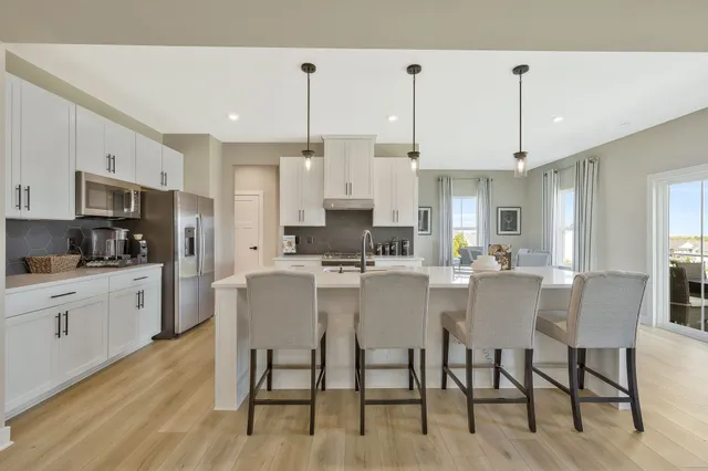 a kitchen with stainless steel appliances kitchen island granite countertop a dining table chairs and white cabinets
