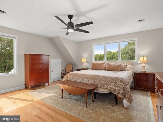 an empty room with wooden floor chandelier fan and windows