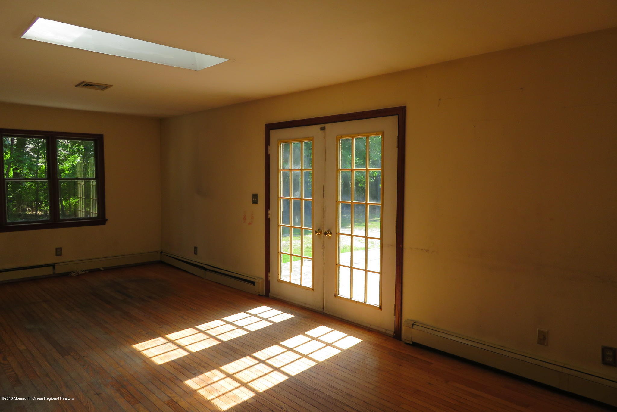 310 Colts Neck Road Farmingdale, NJ 07727 - Photo 6 of 15 an empty room with wooden floor and windows