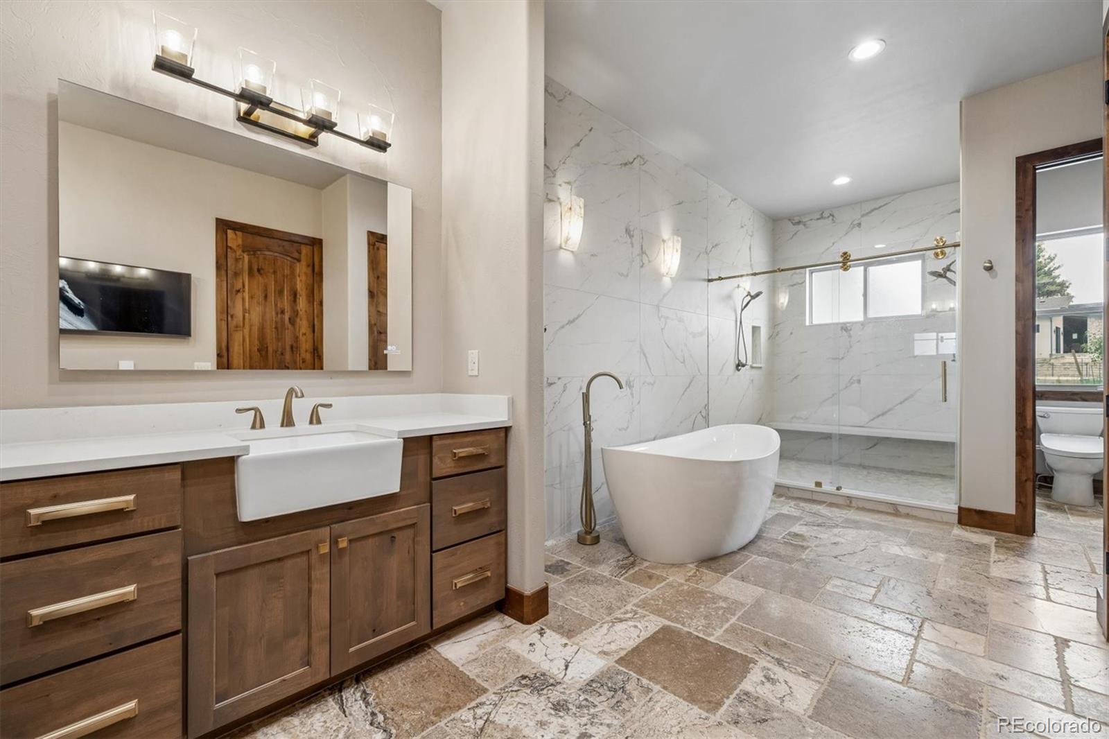 5754 Powell Road Parker, CO 80134 - Photo 21 of 43 a bathroom with a bathtub shower sink mirror and toilet