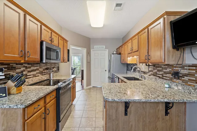 a kitchen with granite countertop a sink a counter top space appliances and cabinets