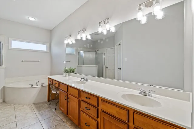 a spacious bathroom with a double vanity sink a large mirror and a bathtub