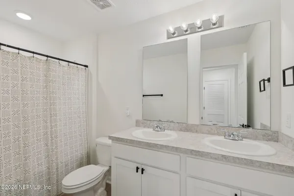 a bathroom with a double vanity sink toilet and a mirror