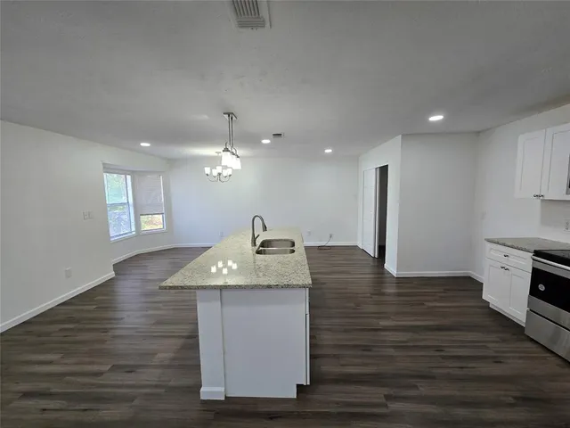 a large white kitchen with kitchen island wooden floors and stainless steel appliances