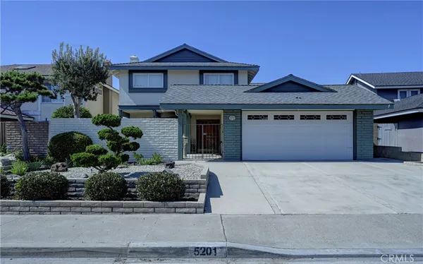 a front view of a house with garage and plants
