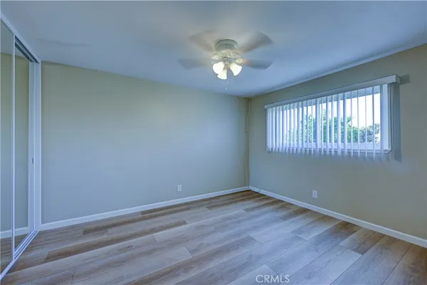 a view of empty room with wooden floor and fan
