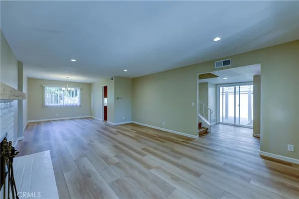 an empty room with wooden floor chandelier and windows