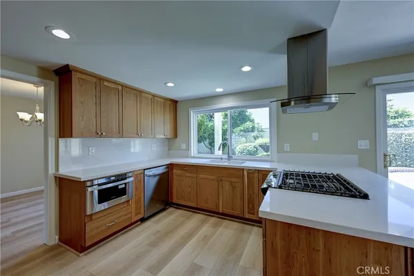 a kitchen with stainless steel appliances granite countertop wooden cabinets and a large window