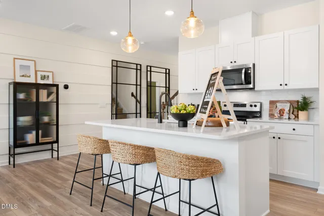 a kitchen with stainless steel appliances granite countertop a refrigerator a sink dishwasher a dining table and chairs with wooden floor