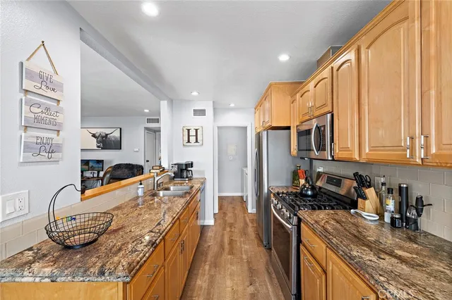 a kitchen with stainless steel appliances granite countertop a stove a sink and a refrigerator