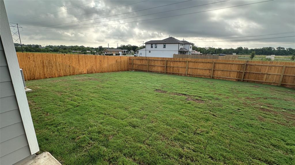 204 Inks Lane Kyle, TX 78640 - Photo 24 of 25 A spacious backyard enclosed by a sturdy wooden fence, perfect for outdoor activities.