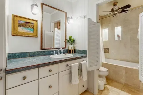 a bathroom with a granite countertop sink a toilet a mirror and shower