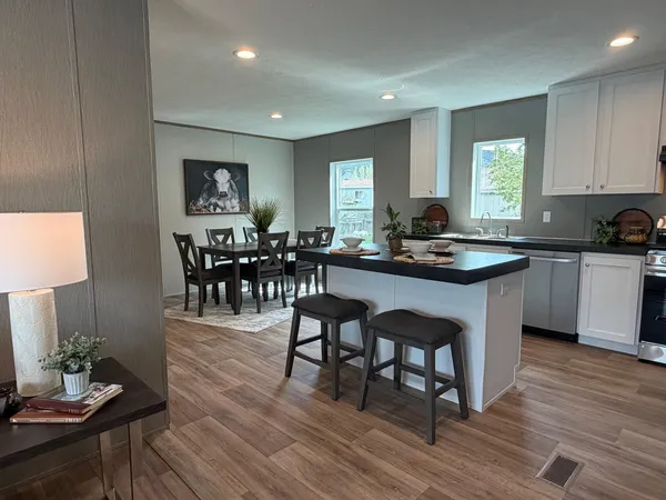 a kitchen with stainless steel appliances granite countertop wooden floor a dining table and chairs