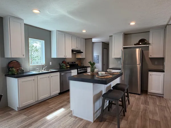 a kitchen with kitchen island a counter top space a sink stainless steel appliances and cabinets