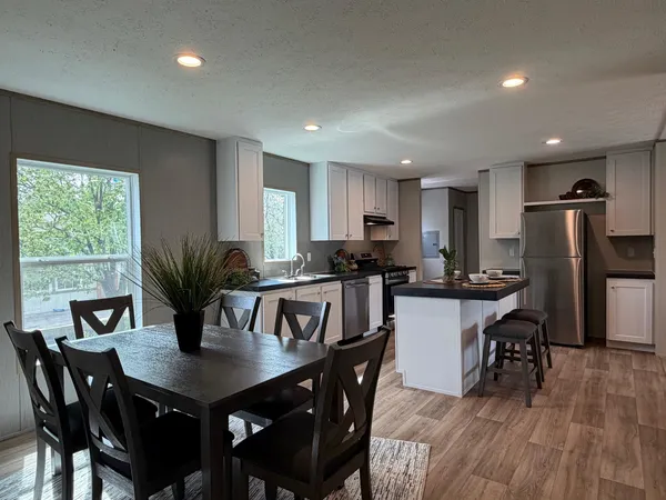 a kitchen with stainless steel appliances granite countertop a dining table chairs stove refrigerator and cabinets