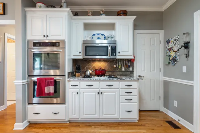 a kitchen with stainless steel appliances granite countertop wooden floors and white cabinets