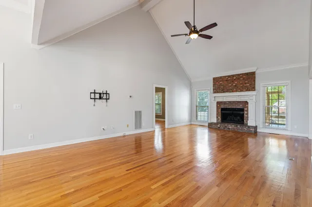 an empty room with wooden floor fireplace and windows