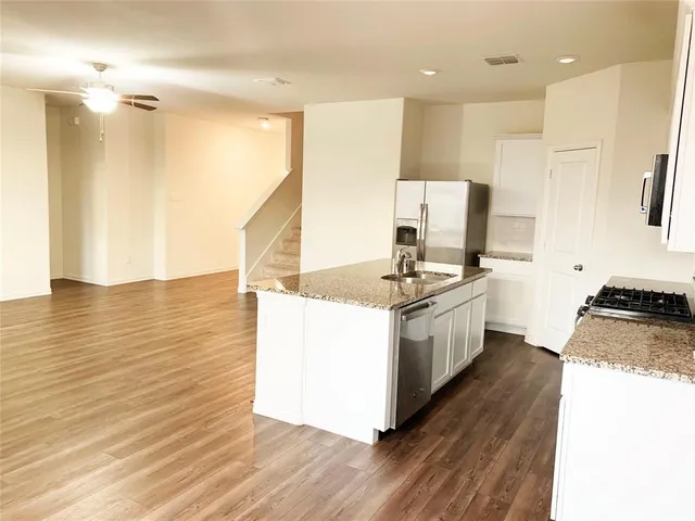 a large kitchen with stainless steel appliances granite countertop a stove a sink and a refrigerator