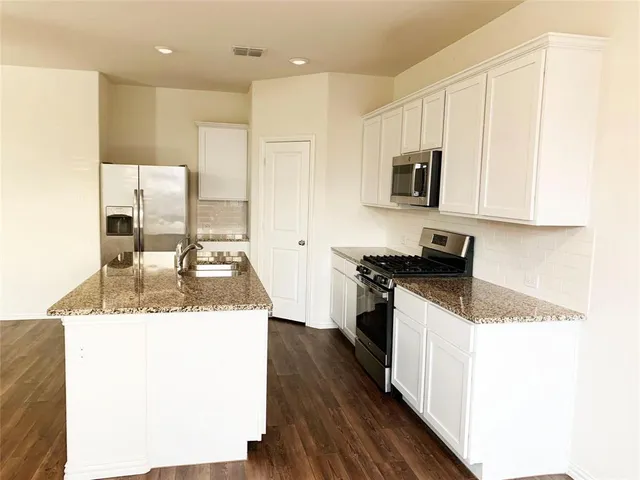 a kitchen with stainless steel appliances granite countertop a sink and a stove