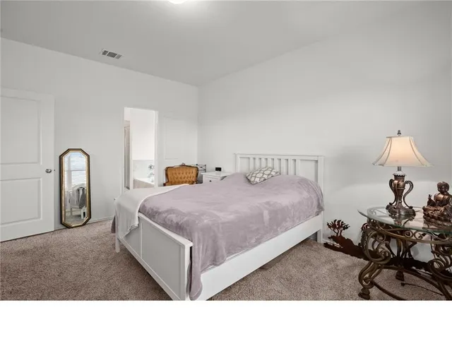 a spacious bedroom with a bed a table and a mirror
