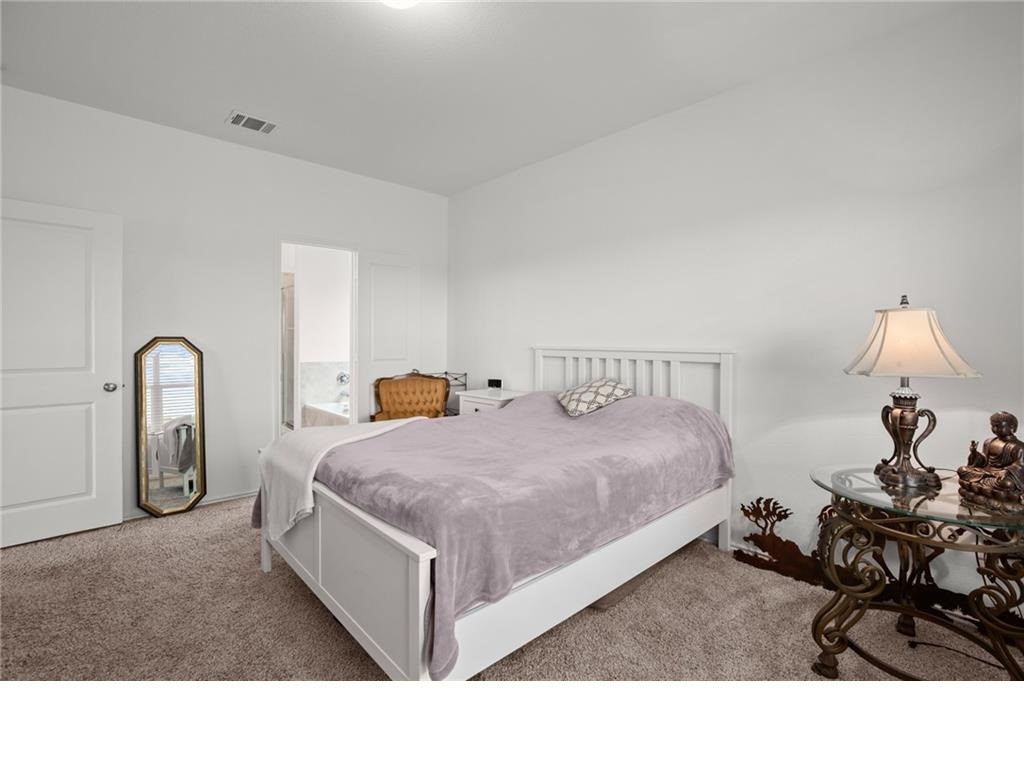 328 Majestic Cedar Court Liberty Hill, TX 78642 - Photo 12 of 31 a spacious bedroom with a bed a table and a mirror