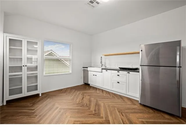a kitchen with white cabinets and wooden floor