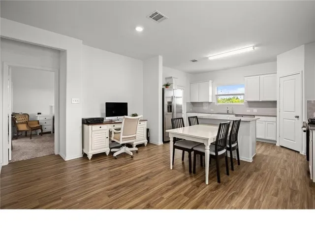 a living room with stainless steel appliances dining table chairs and a refrigerator