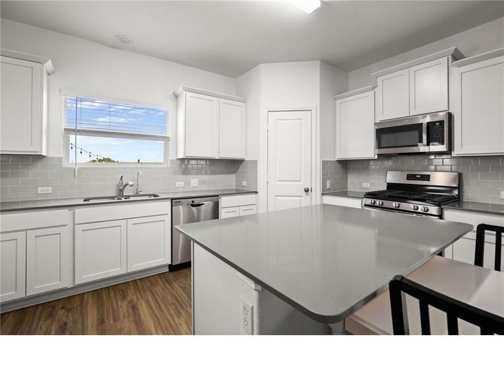 328 Majestic Cedar Court Liberty Hill, TX 78642 - Photo 8 of 31 a kitchen with a sink a stove a microwave and cabinets