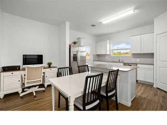 a kitchen with stainless steel appliances kitchen island granite countertop a table chairs and a refrigerator