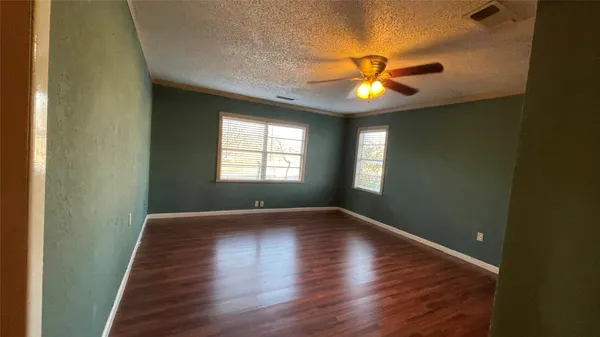 a view of a room with wooden floor and a ceiling fan