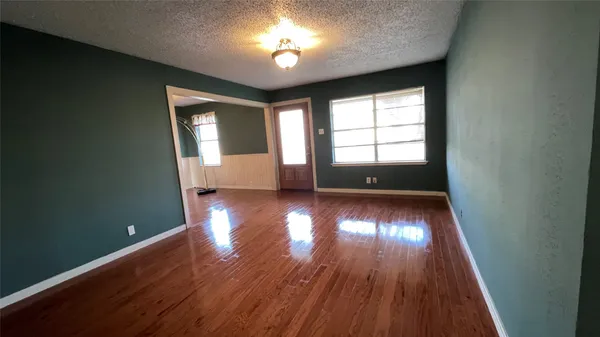 a view of empty room with window and wooden floor