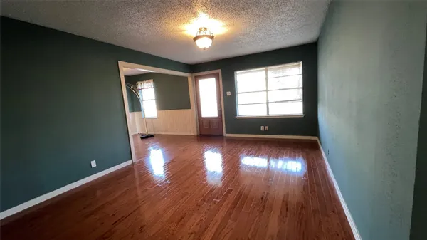 a view of empty room with window and wooden floor