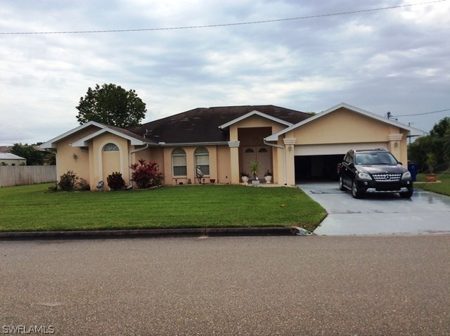 225 Danby Road Lehigh Acres, FL 33936 - Photo 1 of 20 a front view of a house with a garden