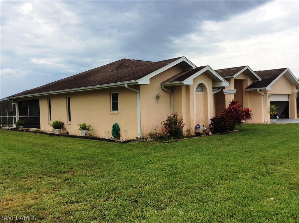 225 Danby Road Lehigh Acres, FL 33936 - Photo 3 of 20 a front view of a house with a garden