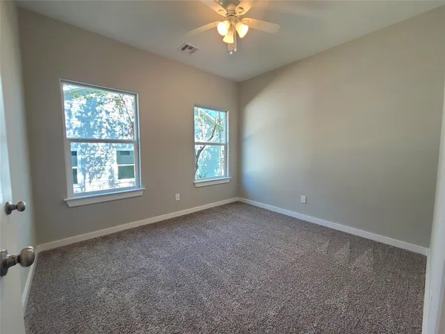 an empty room with windows and chandelier fan