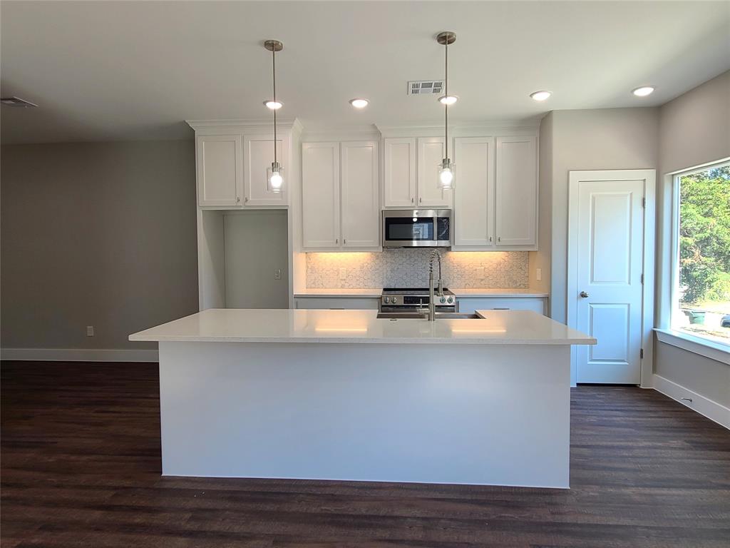 507 Northeast 5th Avenue Durant, OK 74701 - Photo 19 of 35 a large kitchen with granite countertop a stove a sink a refrigerator and a wooden floor