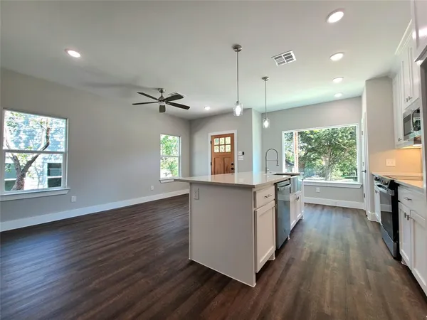 an open kitchen with wooden floor and windows