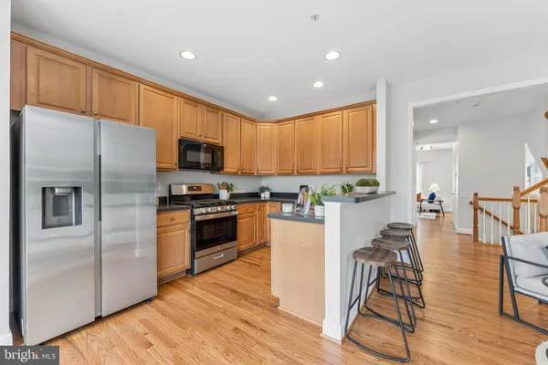 a kitchen with stainless steel appliances granite countertop a refrigerator a stove top oven a sink dishwasher and white cabinets with wooden floor
