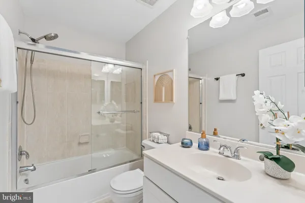 a bathroom with a bathtub shower sink vanity mirror and toilet